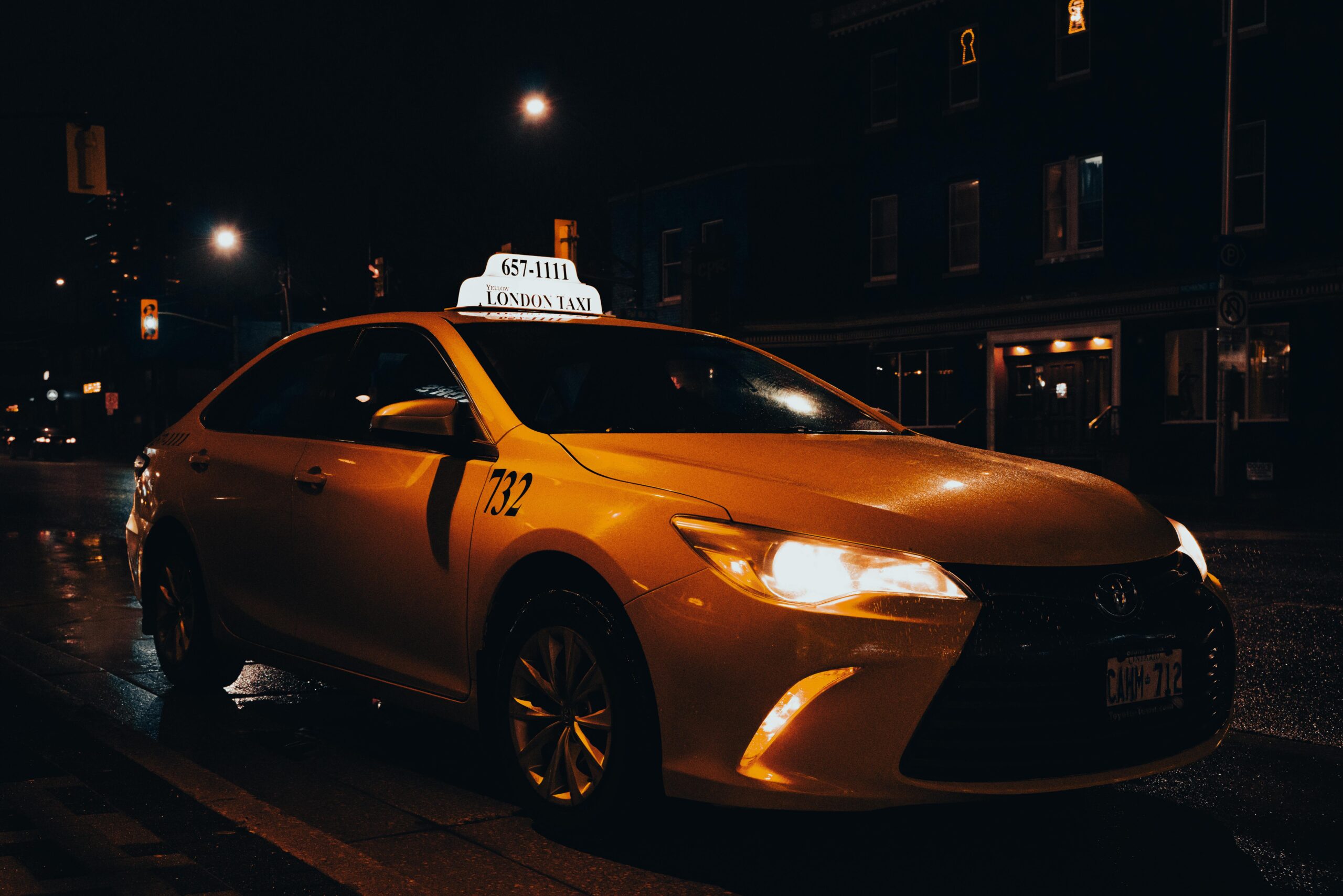A yellow taxi waiting at night in London, Ontario, Canada. Urban transportation captured with street lights.