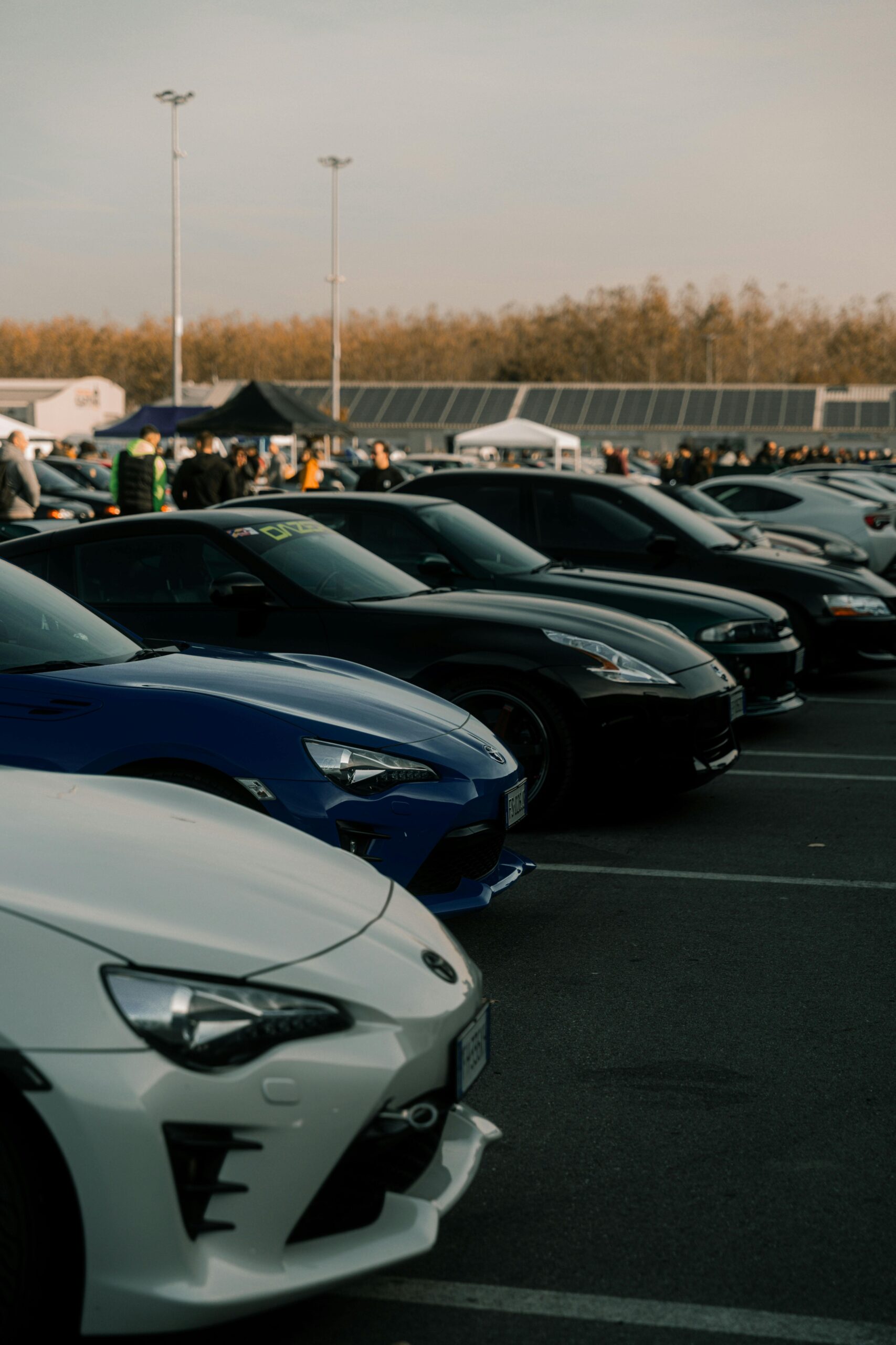 Lineup of sports cars at an outdoor event in Cremona, Italy, showcasing automotive diversity.