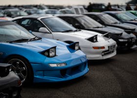 Toyota MR2 sports cars with popup headlights showcased at a car meet in England.