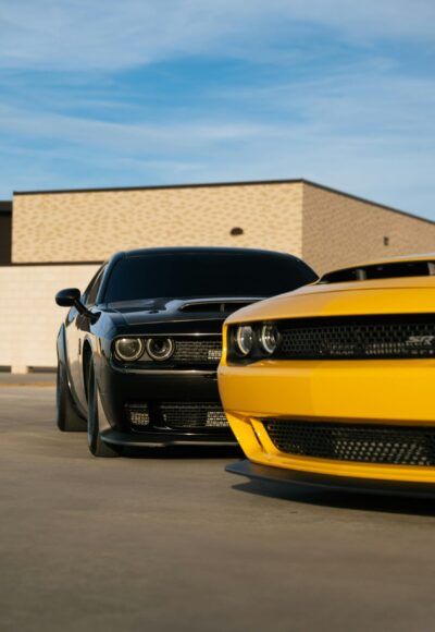 A black and yellow muscle car side by side in an outdoor parking area.