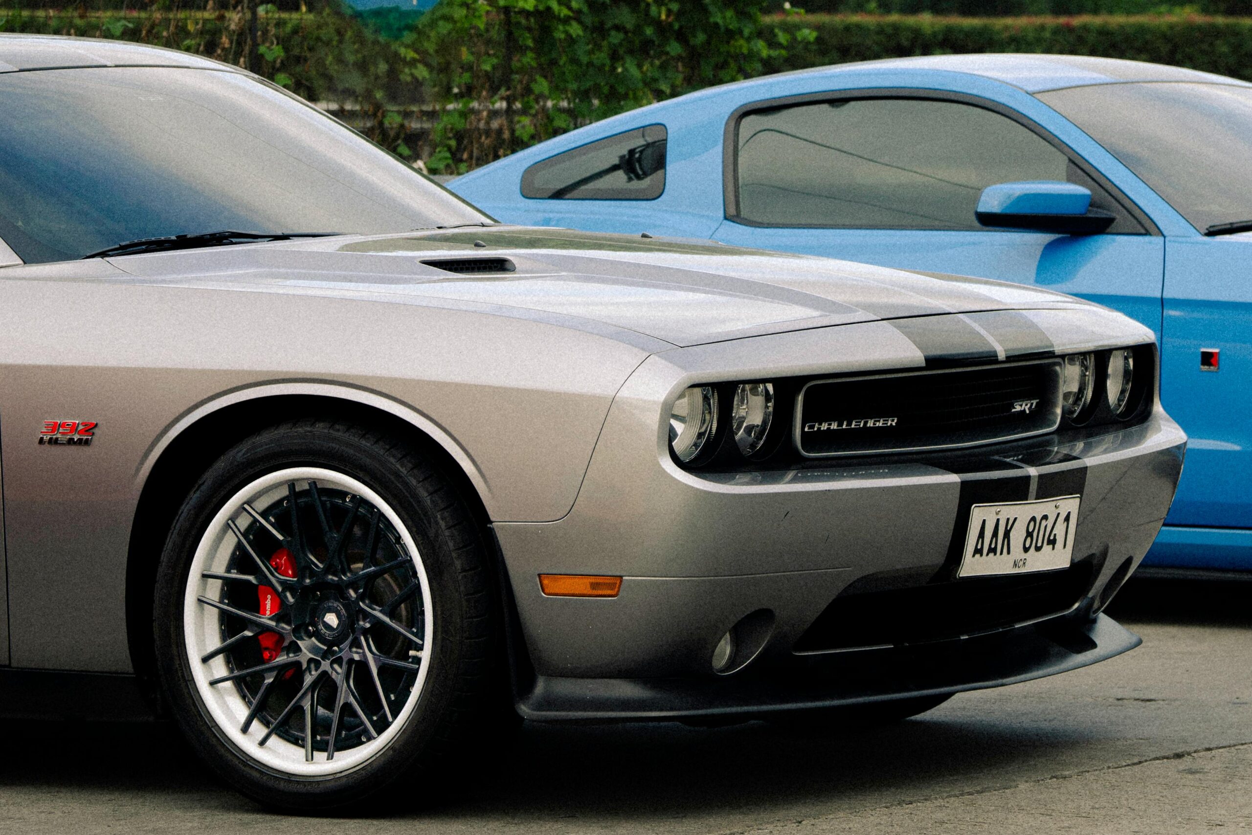 Silver Dodge Challenger and blue Ford Mustang parked outdoors, showcasing automotive design.